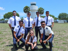 A group of cadets posing for a photo in front of an Air Traffic Control Tower